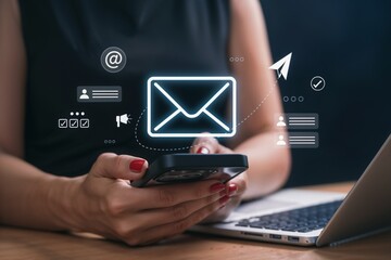 Close-up of woman using smartphone with laptop, glowing email icon, and digital communication graphics. Concept of email marketing, online messaging, social media, and digital communication.
