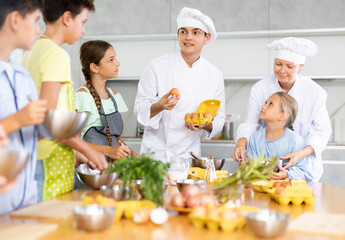 During lesson in cooking courses, male cook professional tells children about rules ticks and...