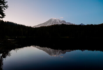 Calm Reflection Lake with mirror-like surface reflecting surrounding mountains and trees. Serene nature scene perfect for outdoor and landscape photography.