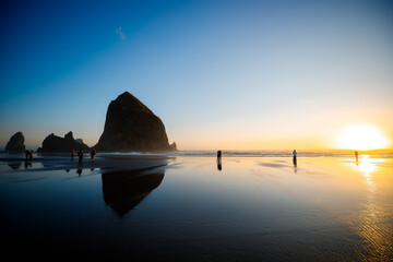 Cannon Beach at golden hour, featuring Haystack Rock and gentle waves. Coastal landscape at sunset on the Oregon Coast, popular travel and nature destination.