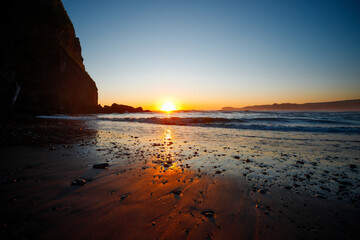 Sunset at Ruby Beach, Olympic National Park, Washington State. Colorful sky reflecting on wet sand with sea stacks and gentle ocean waves.
