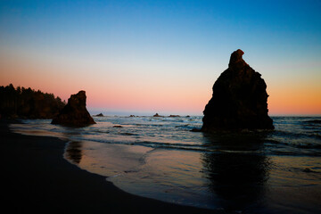 Sunset at Ruby Beach, Olympic National Park, Washington State. Colorful sky reflecting on wet sand with sea stacks and gentle ocean waves.