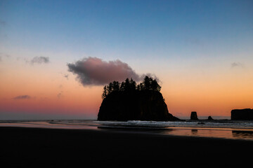 Sunset at Second Beach, Olympic National Park, Washington. Silhouettes of sea stacks and gentle ocean waves under a glowing sky.