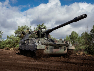 Low angle view of PzH 2000NL artillery system positioned in muddy terrain with dramatic sky