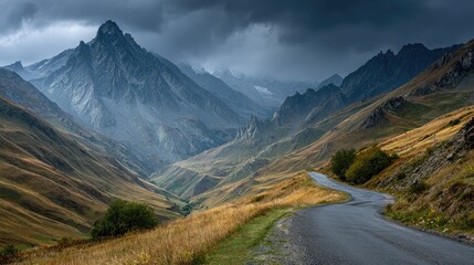 Mountain road winds through autumnal valley under dramatic sky