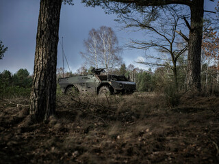 Armored reconnaissance vehicle positioned strategically among forest trees for surveillance