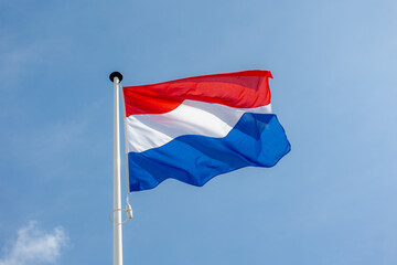 National flag of the Netherlands with horizontal tricolour of red, white and blue, Dutch flag waving on the air in a sunny day and blue sky background.