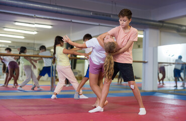 Girl and boy training self-defence moves during group training.
