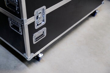 Close-up view of flight case corner showing aluminum edge trim and blue wheel caster mounted on black surface