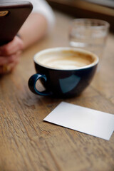 Close-up of business card and coffee cup with smartphone creating professional atmosphere