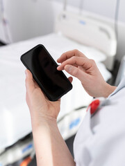 Healthcare worker in white coat using smartphone for medical communication and coordination