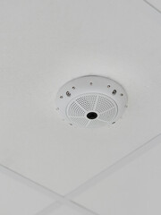 Close-up view of ceiling-mounted surveillance camera with white housing and multiple mounting screws