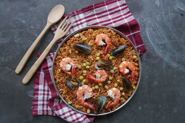 Paella is a Spanish dish made from rice, seafood, shrimp, clams, lemon, peas with saffron seasoning.