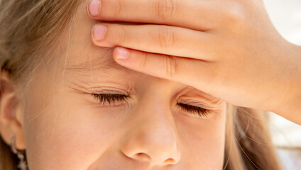 Young child holding head in pain, Six-year-old girl suffering from headache, concussion symptoms,...