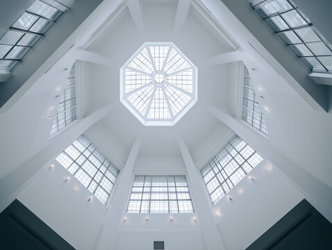 Interior de edificio moderno con techo acristalado en patr&oacute;n geom&eacute;trico que permite entrada de luz natural, resaltando est&eacute;tica minimalista, espacios abiertos y dise&ntilde;o arquitect&oacute;nico contempor&aacute;neo