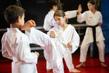Child boy and girl partners during martial arts karate class train to perform basic blows to...