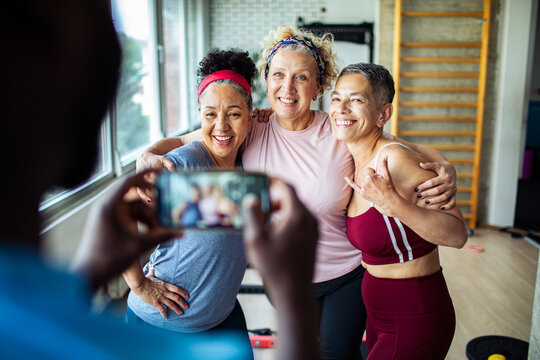 Three senior women friends posing for a photo together after workout in gym