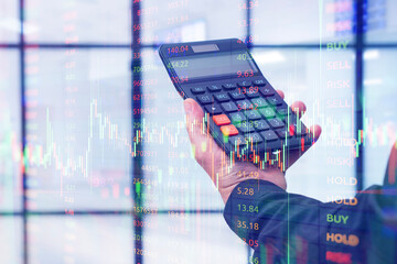Businessman hand holding calculator with digital overlay of stock market charts and numbers. Concept of finance, cryptocurrency trading, accounting, investment planning and fintech.