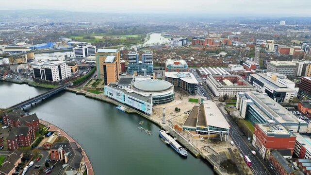 Aerial drone view of cars driving over the buildings surrounding River Lagan