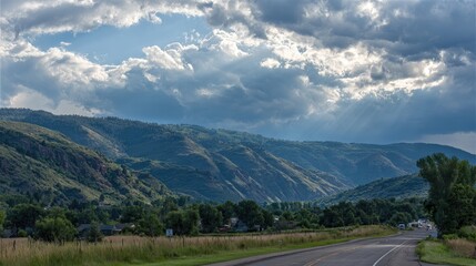 Naklejka premium Mountainous landscape with dramatic clouds and sunlight rays.