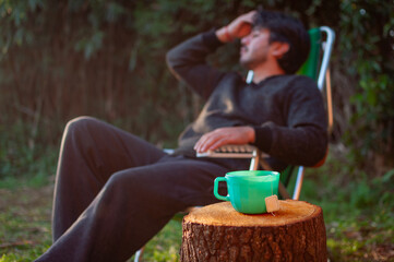 Hombre sentado bebiendo infusión en el jardín. naturaleza, bebida caliente.