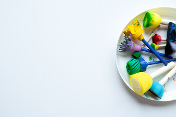 Colorful sponge painting tools on white plate for creative art projects