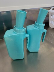 Two plastic male urinals on a clean metallic surface