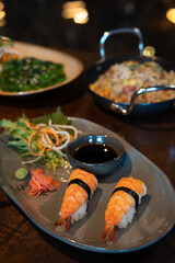Fresh Off nigiri sushi served on a  plate with soy sauce and vegetables