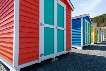 A row of small, colorful painted huts or sheds made of wood. The exterior walls are colorful with...
