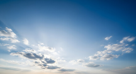 Expansive blue sky with radiant sunbeams breaking through clouds