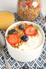Tasty yogurt with granola, berries and honey on table, above view