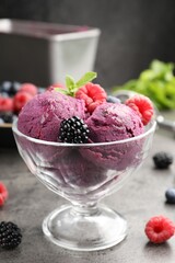 Delicious sorbet with fresh berries and mint in dessert bowl on grey textured table against dark background, closeup