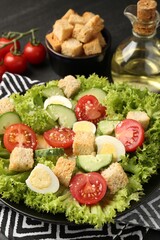 Delicious salad with croutons and ingredients on table, closeup