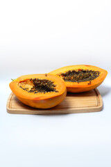 Fresh ripe papaya cut in half placed on a wooden board with bright orange flesh and black seeds, symbolizing tropical fruit, natural nutrition, organic food, and healthy lifestyle.