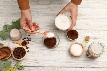 Making natural scrub. Woman adding sugar into bowl at white wooden table, top view
