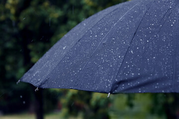 Blue umbrella under heavy rain outdoors, closeup
