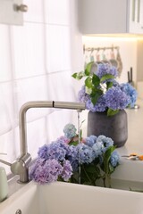 Bouquets of beautiful blue hortensia flowers in kitchen