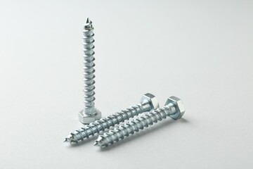 Three metal bolts on light grey background, closeup. Hardware tool