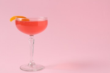 Martini cocktail with garnish on pink background, space for text