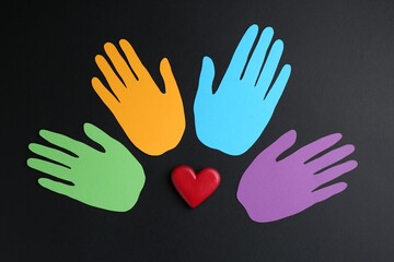Tolerance concept. Colorful paper hands and heart on black background, flat lay