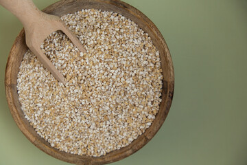 Fine ground barley in green background copy space. Whole spelt grain species. High protein fiber-rich vegan plant based food ingredient. Gluten free superfood healthy nutritional dietary alternative