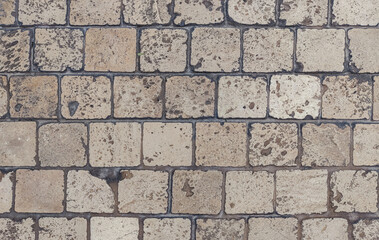 Close-up of stone pavement with square tiles in earthy tones. The rough surface and natural texture...