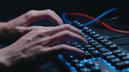 A close-up shot of a hacker's hands typing furiously on a keyboard, with lines of green code reflecting on a monitor screen in a dark room.
- Powered by Adobe