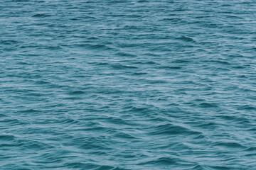 An image of the surface of water with ripples and golden reflections of the sun, creating a vibrant contrast and a feeling of warmth. Ideal for backgrounds, textures and to evoke the beauty of sunrise