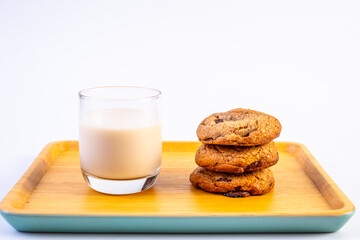 Stack of Dark Chocolate cookies with a cup of milk on wooden plate and on white background