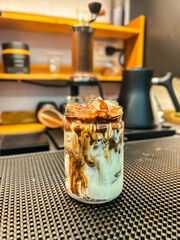 Matcha Biscoff Latte served in a glass cup on a trendy coffee shop background.