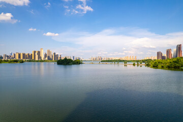 A wide lake reflects the sky near a city skyline with many tall buildings.