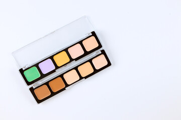 Colorful concealer palette arranged neatly on clean surface with various shades for makeup...