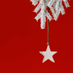 Christmas bauble shiny golden star hanging on green Christmas fir branch on red background with...