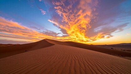 Vibrant desert sunset with orange clouds and sand dunes.